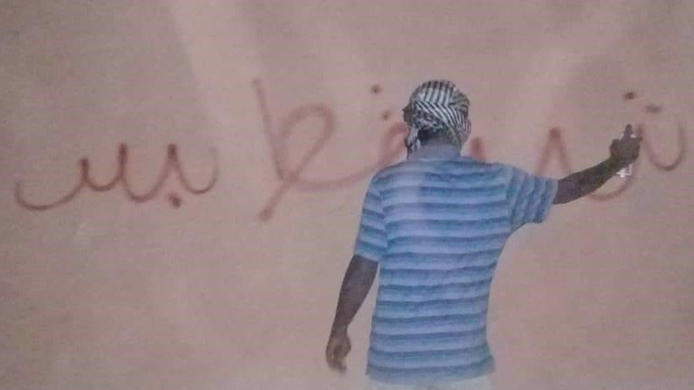 ill Soudanais écrivant sur le mur